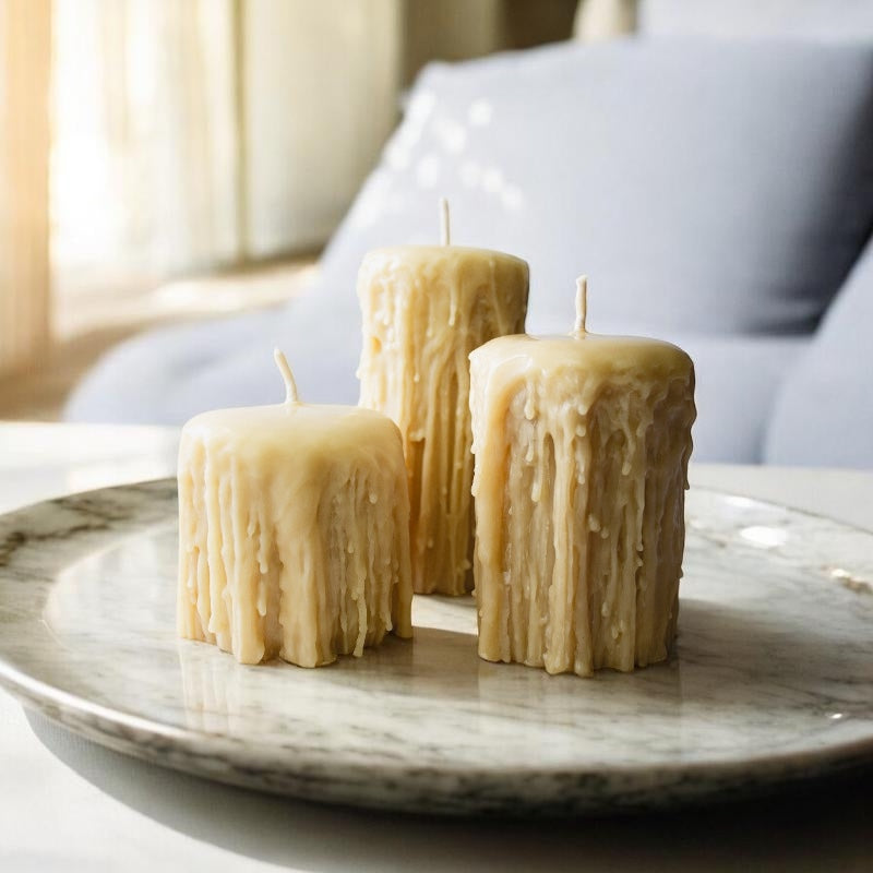 Three textured candles on a marble surface with a blurred indoor background