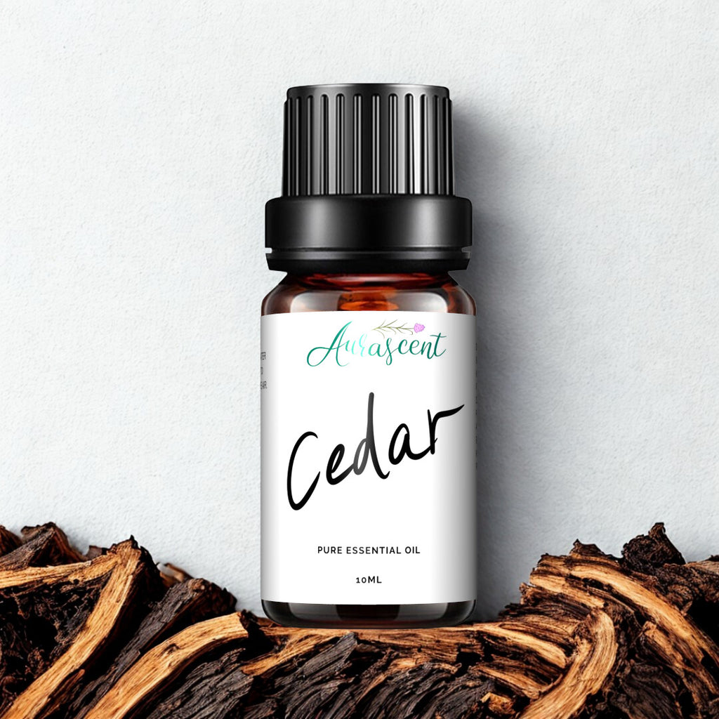A 10ml bottle of Aurascent Cedar Essential Oil with a clear label, set against a natural wooden background.